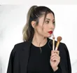 Retrato de Bianca Padilla con dos brochas de maquillaje en la mano